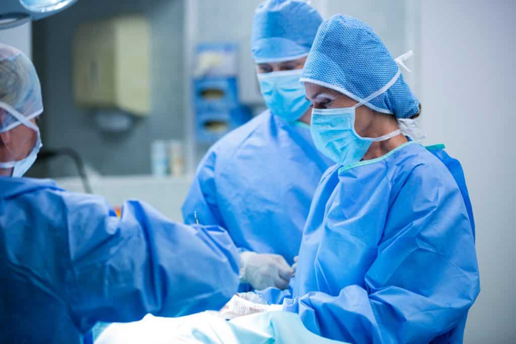 一群穿着手术服、戴着手术帽的外科医生正在进行包皮环切手术。