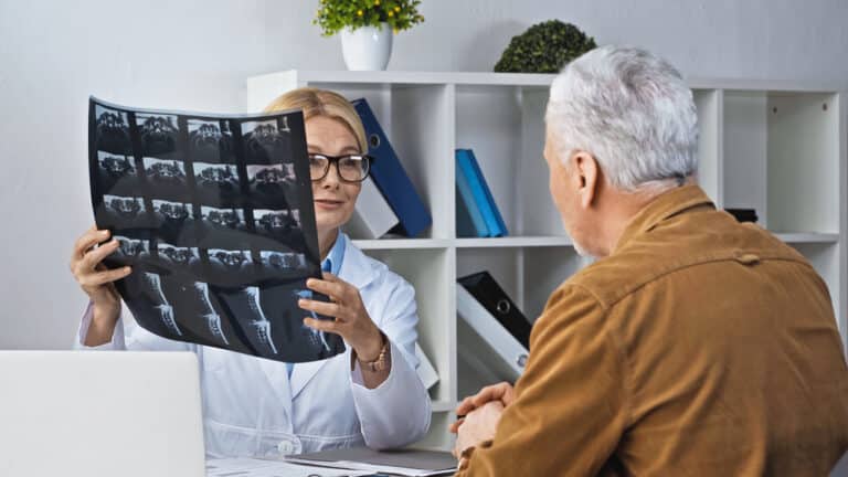 A doctor demonstrating an x-ray utilizing the history of digital radiography to a patient.