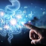 A hand is pointing at a digital image of a digestive system, highlighting the connection between circumcision and the microbiome.