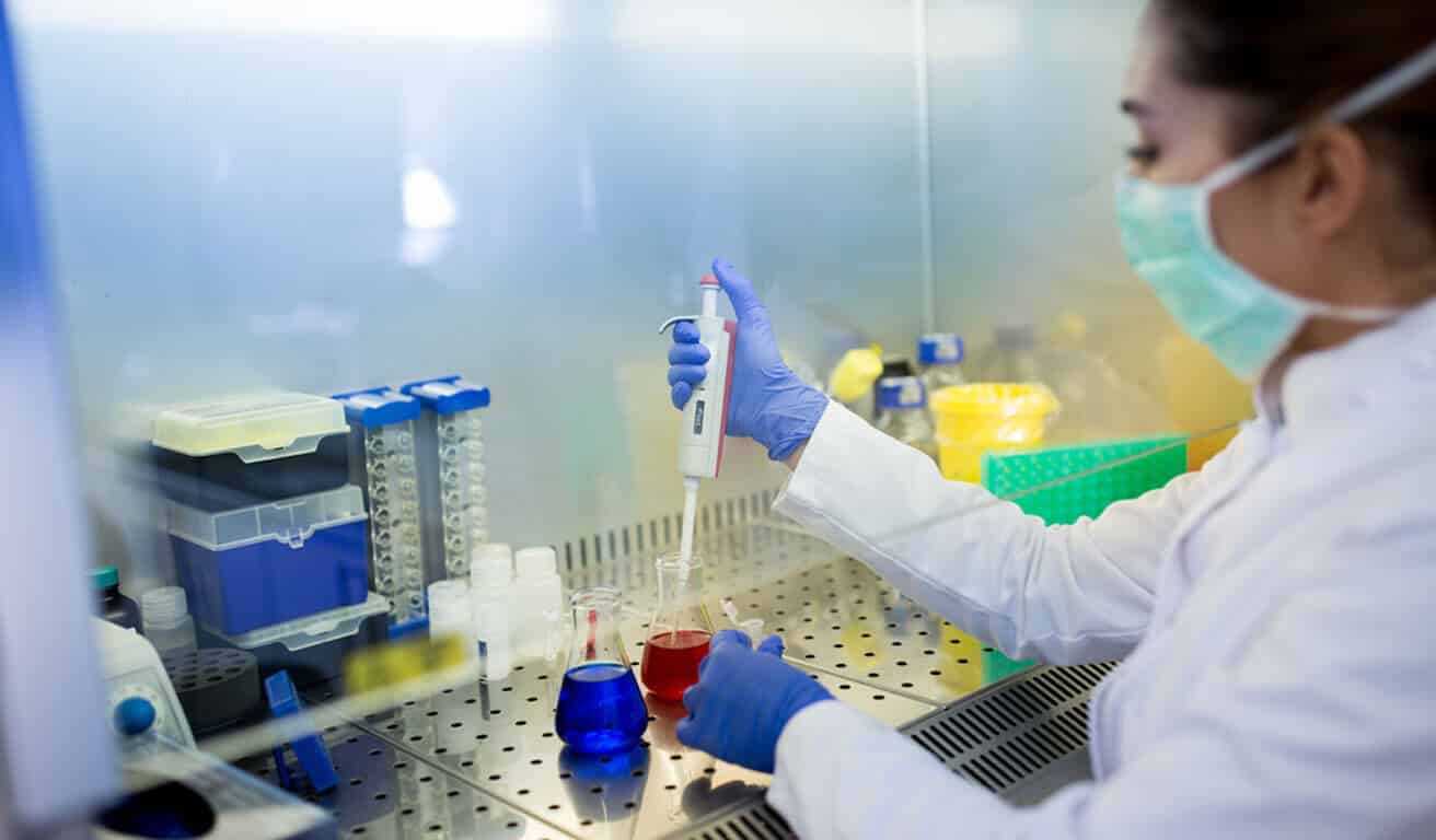 A woman in a lab coat meticulously working on a test tube, exploring the impact of technology on healthcare.