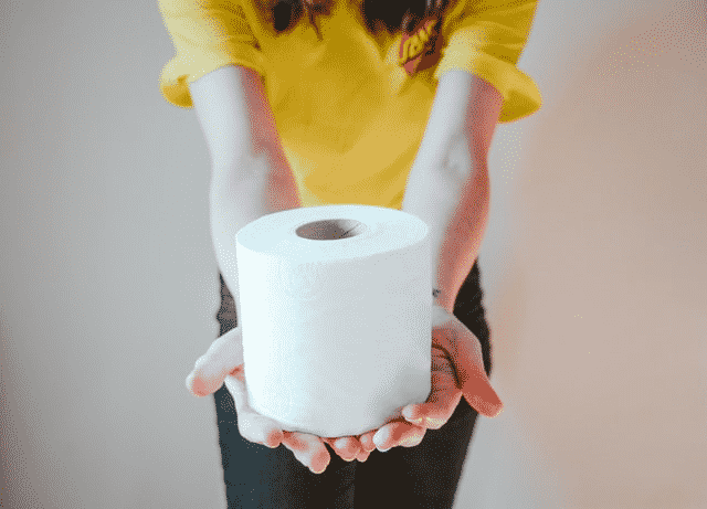 A woman holding a roll of toilet paper for cleaning private parts after urination.