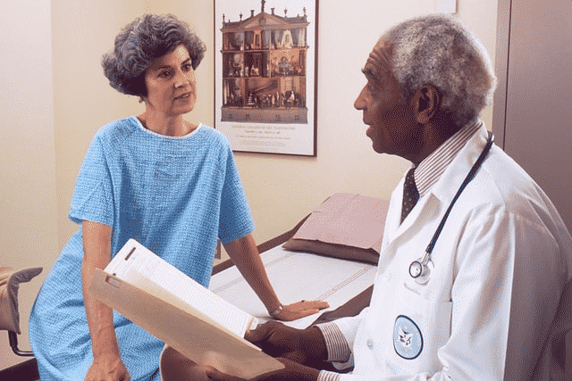 A doctor is discussing hygiene practices with a patient in a hospital room.